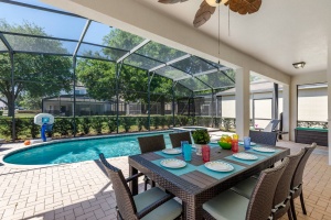 Outdoor Covered Lanai with seating for 8, 4 lounge chairs, a ceiling fan and 3 burner stainless steel BBQ.
